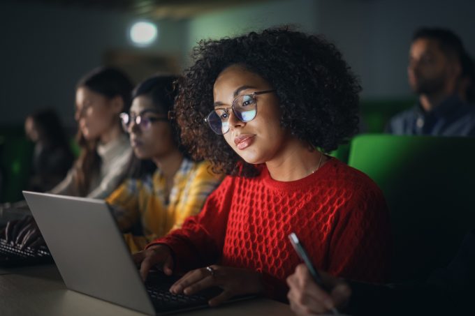 Beautiful Multiethnic African Female Student Studying in University with Diverse Classmates. Young Black Woman Using a Laptop Computer. Applying Her Knowledge to Acquire Academic Skills in Class
