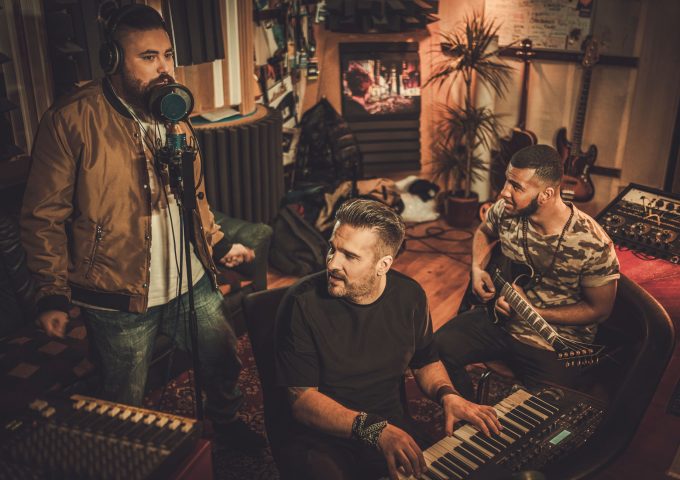 Professional music band recording song in boutique recording studio.